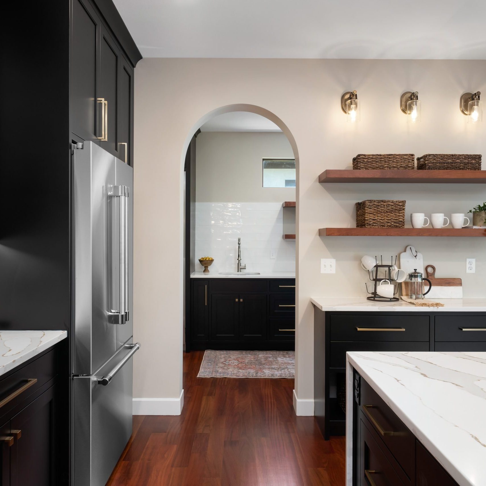 Kitchen into pantry with waterfall style kitchen island and walkway black custom cabinetry.