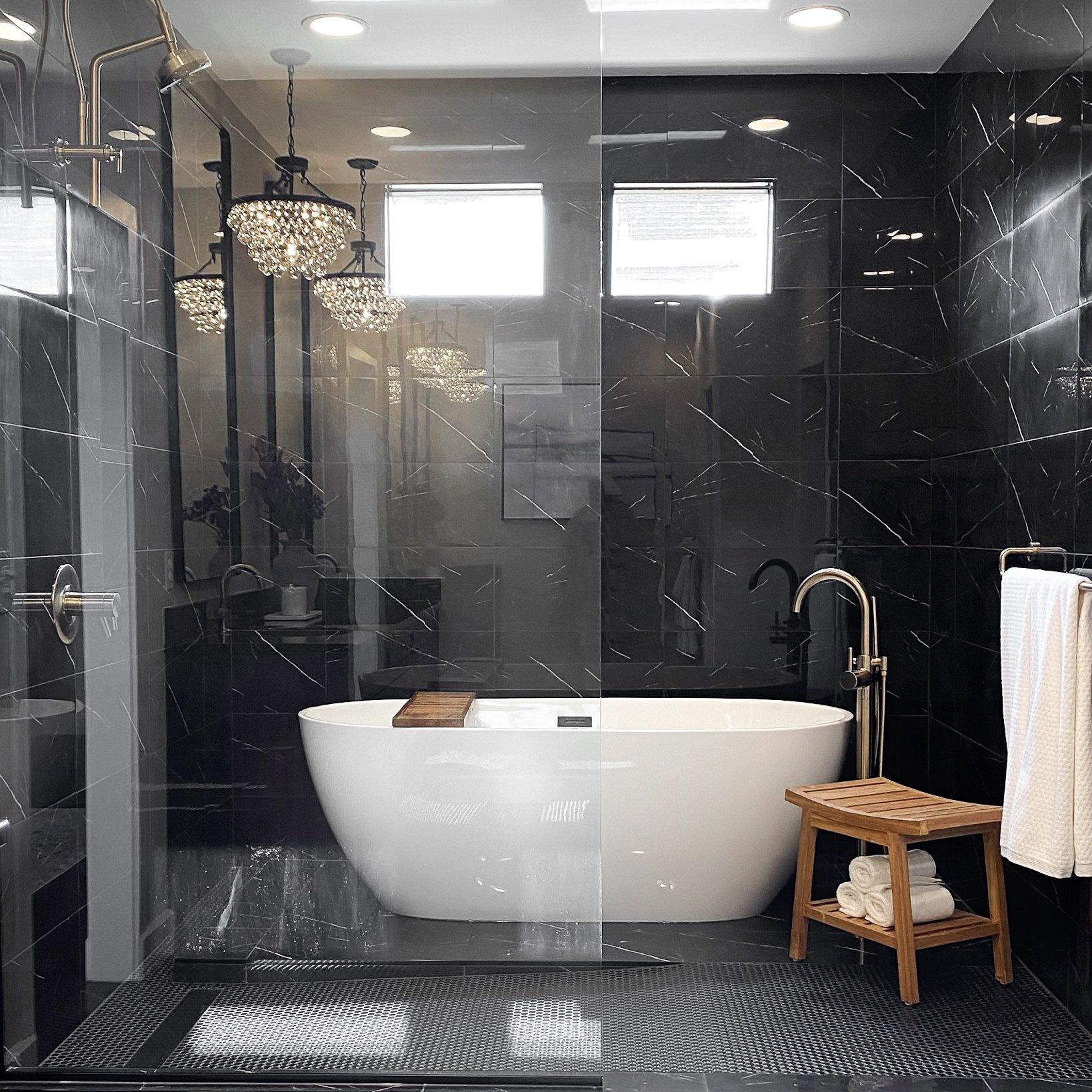 Luxury bathroom with black marble, white bathtub and walk-in shower.